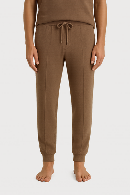 Brown jogger pants worn by a person on a white background