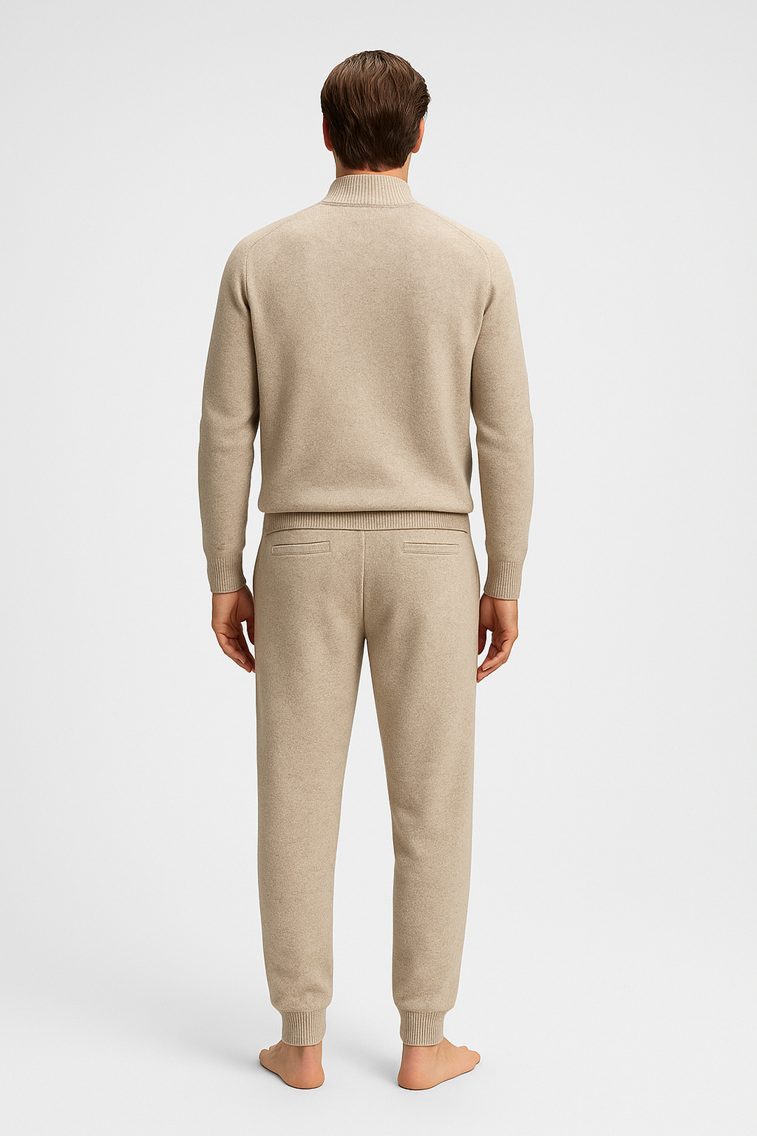 Man wearing a beige sweater and pants on a white background