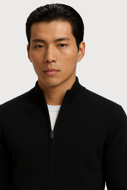 Man wearing a black jacket over a white shirt on a light gray background