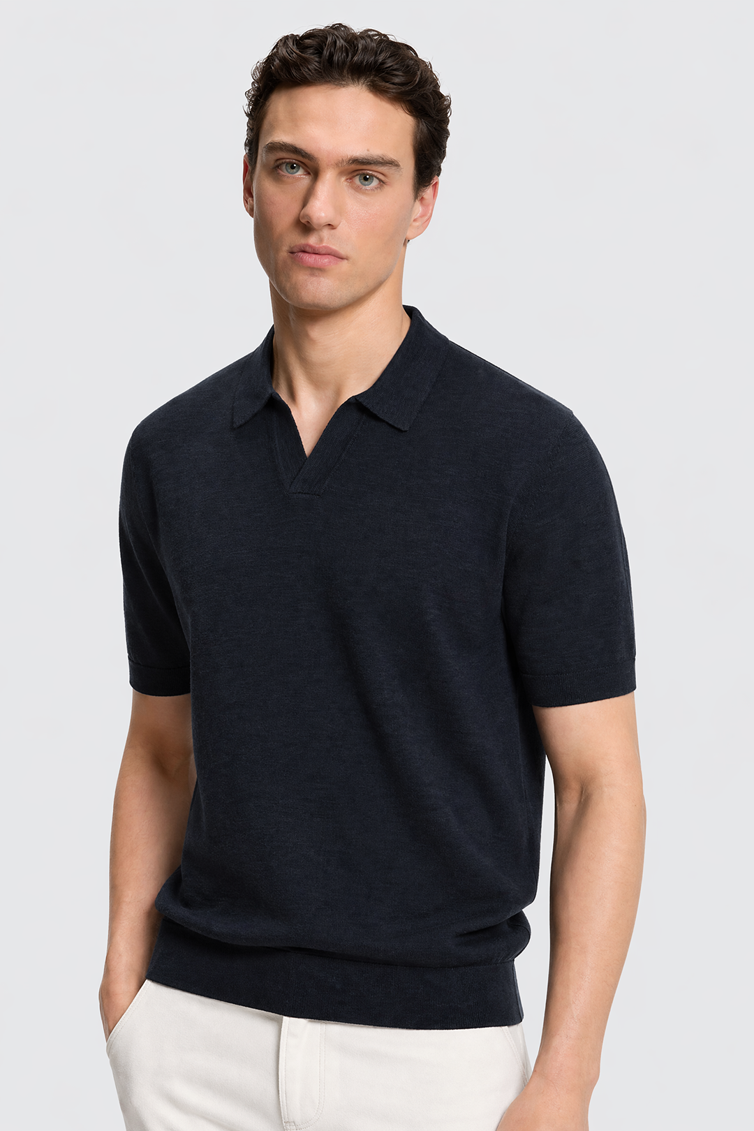 Man wearing a dark blue polo shirt against a light gray background