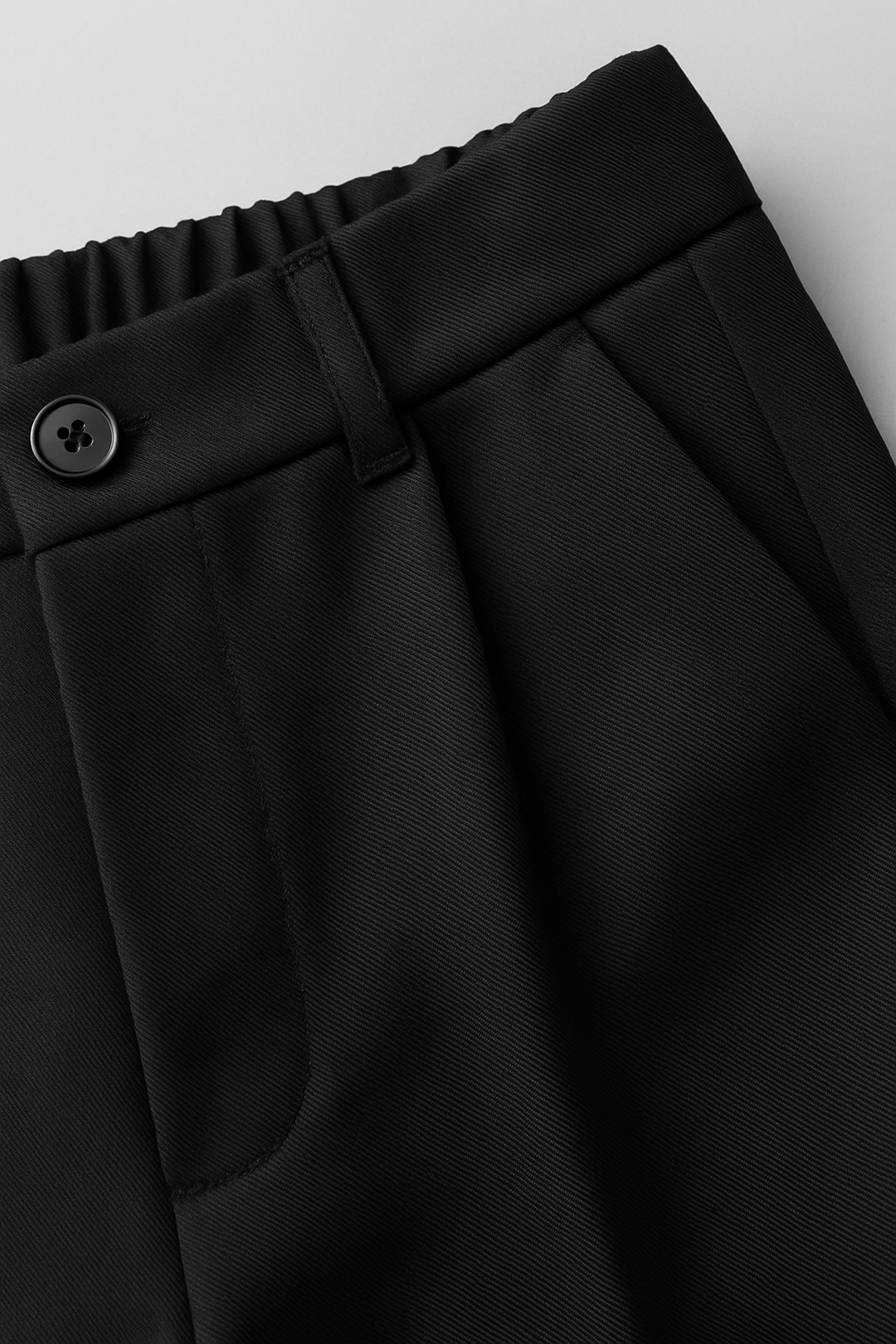 Close-up of black pants with a button on a light gray background