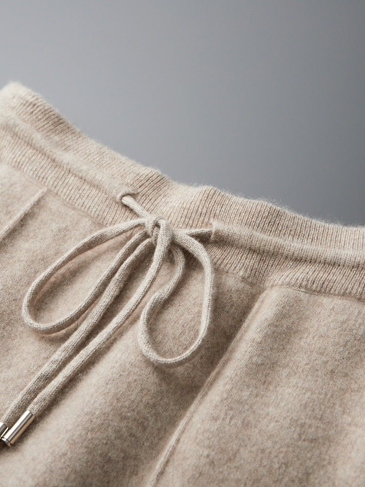 Close-up of beige sweatpants with a drawstring on a gray background