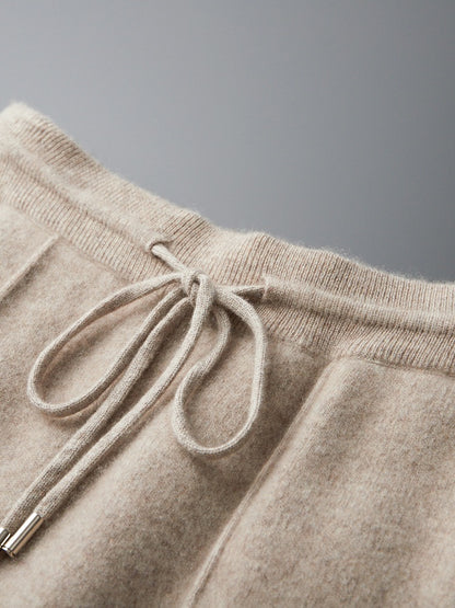 Close-up of beige sweatpants with a drawstring on a gray background