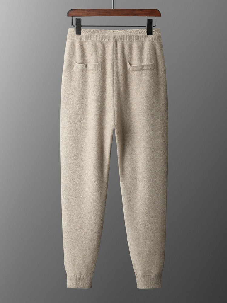 Beige sweatpants on a hanger against a gray background