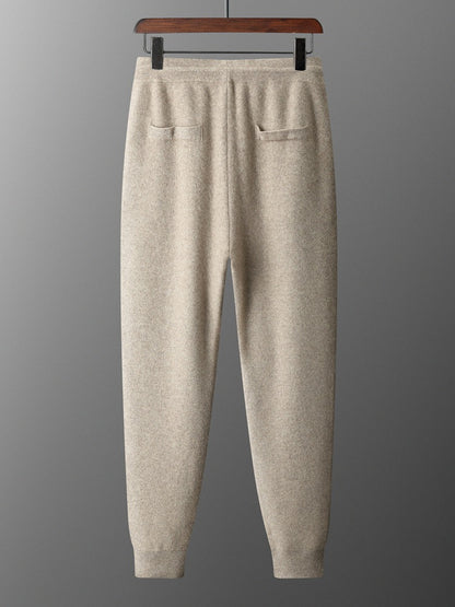 Beige sweatpants on a hanger against a gray background