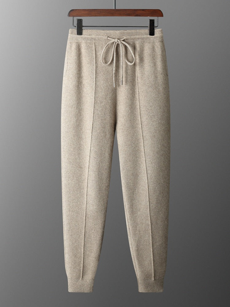 Beige sweatpants on a hanger against a gray background