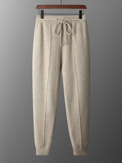 Beige sweatpants on a hanger against a gray background