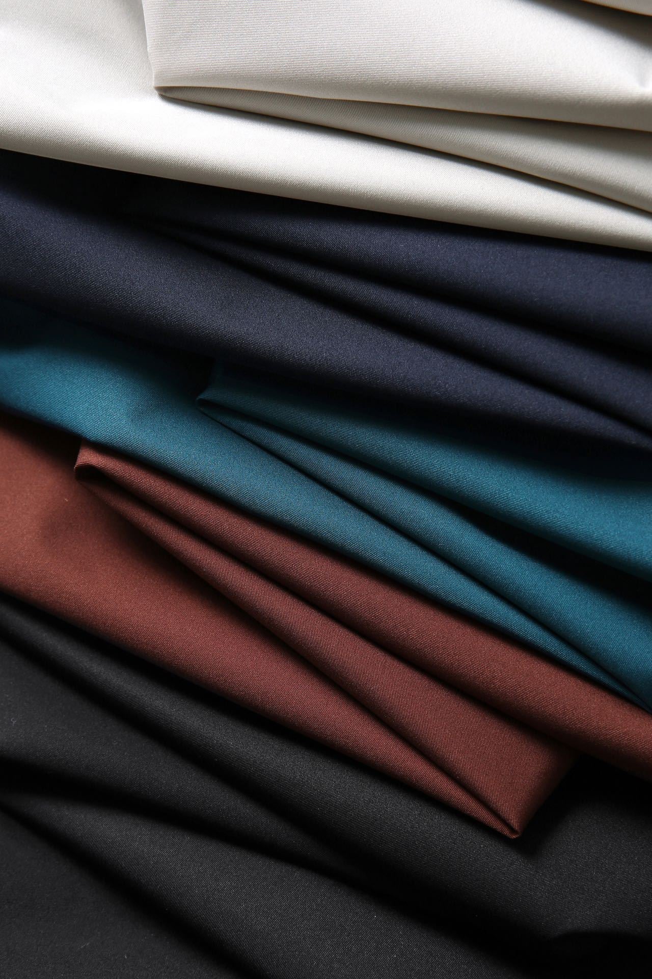 Close-up of folded fabric in various colors including black, blue, brown, and white.