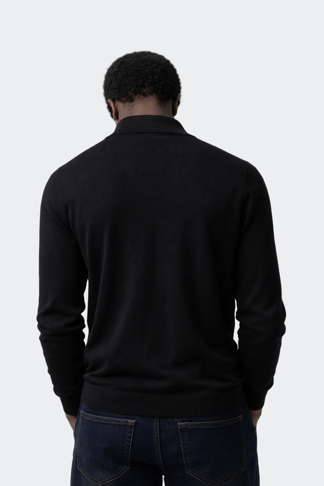 Person wearing a black sweater and jeans on a white background